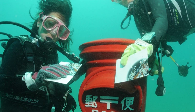 两个女生水潜水至海底将明信片投入邮筒