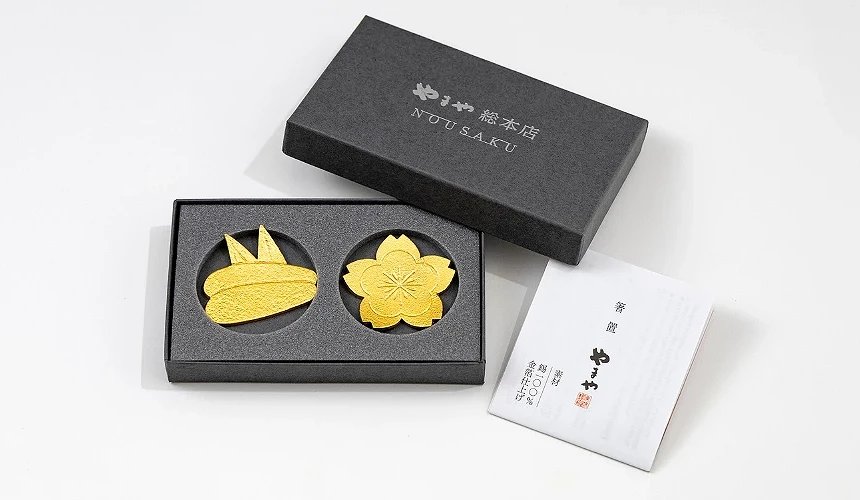 黑色禮盒內放置兩個金色飾片,外盒上寫有日文標語