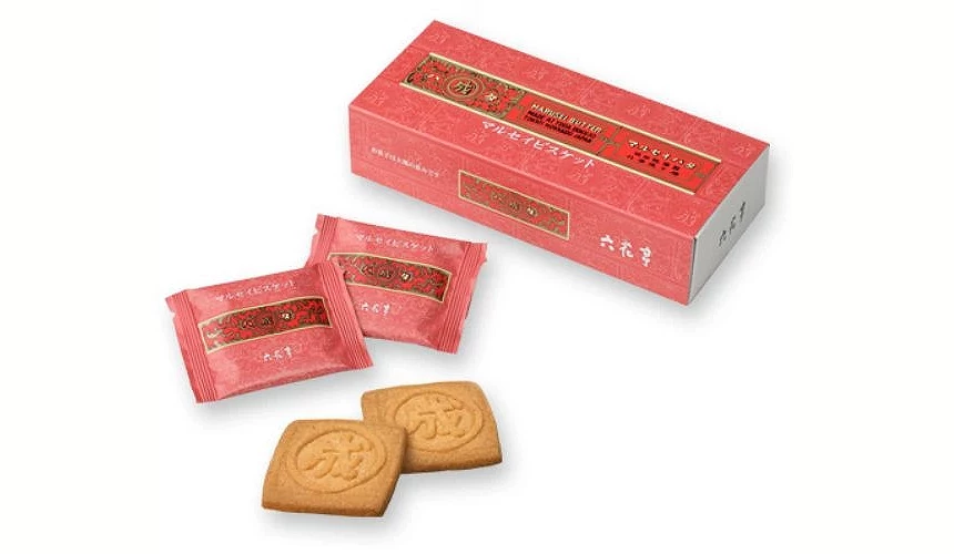 奶油饼干的包装与实物示意,红色外盒与独立包装上印有复古花纹与「◯成」标志,前方摆放两片金黄酥脆的奶油饼干,可见经典压印图样