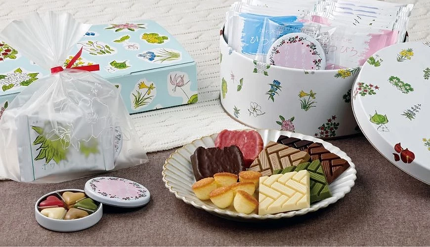 六花亭礼盒与多款点心摆盘,包含彩绘铁盒、独立包装饼干与巧克力,以花卉图案包装呈现北海道特色
