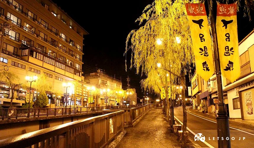 下吕温泉的夜景,河畔步道在黄灯照映下显得宁静迷人,街边挂有写着「下吕温泉」的旗帜