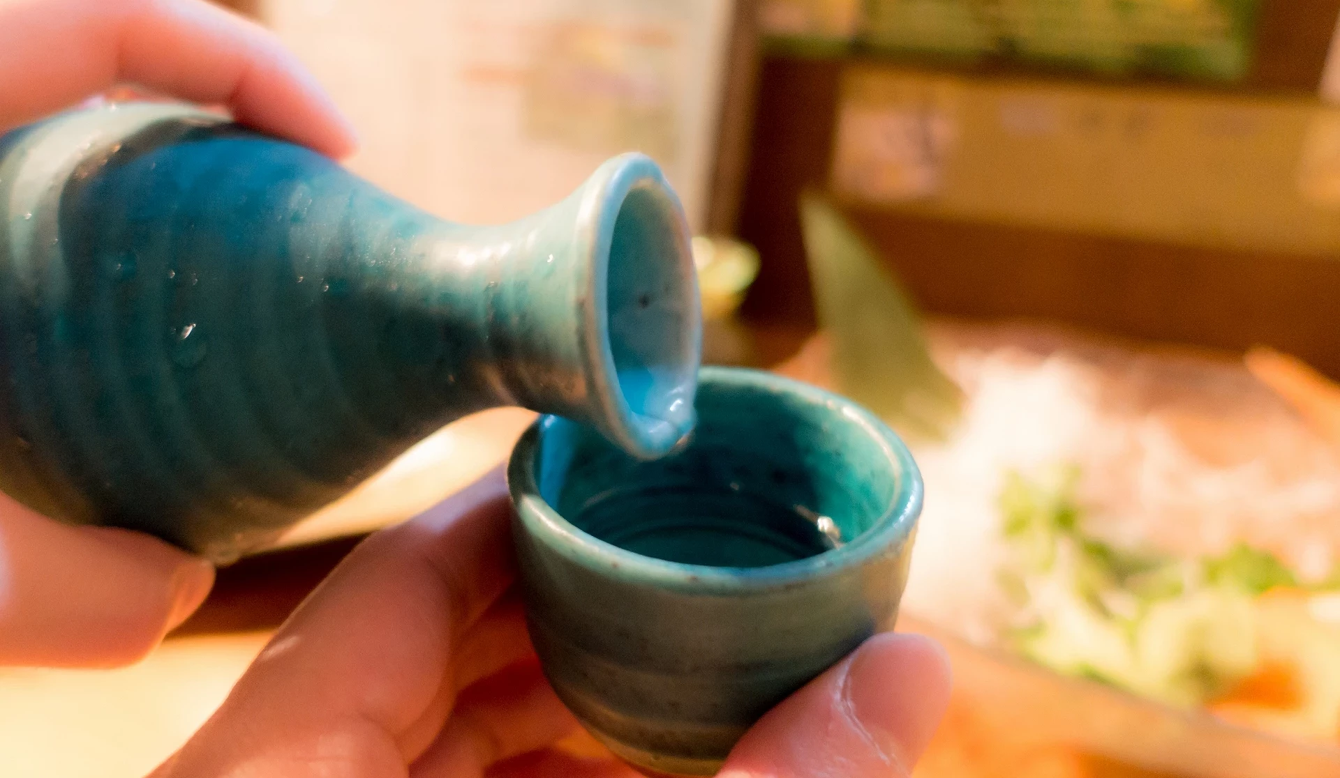 將清酒倒入藍綠色杯子