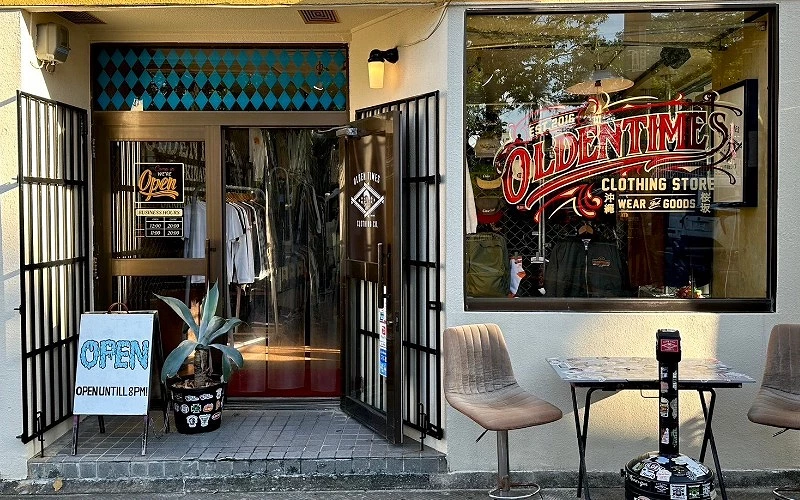 服飾店外觀為黑色鐵門,右邊是一面有貼圖案的窗戶,外面有兩張椅子和一張桌子