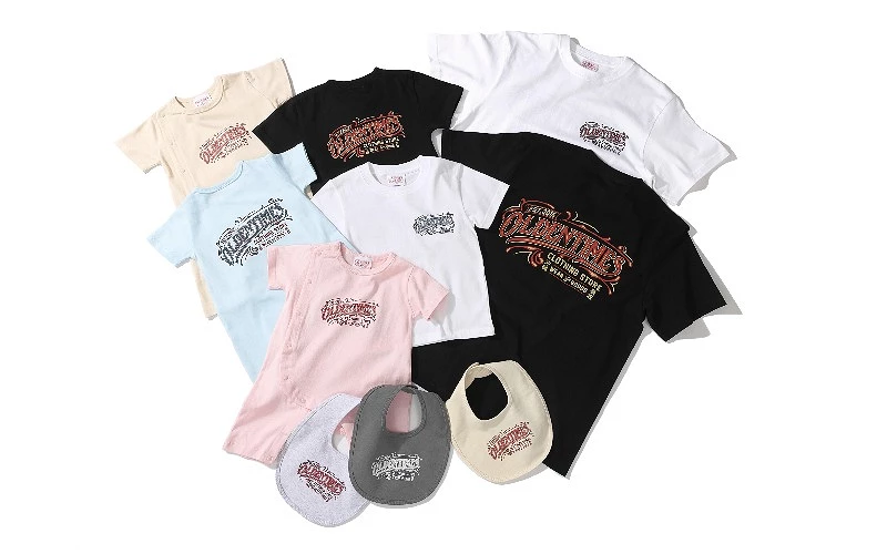 多件不同尺寸 T 恤與童裝平鋪,胸前印有 OLDEN TIMES 標語,搭配三款口水巾