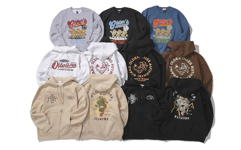 多件帽T與拉鍊連帽外套平鋪排列,印有 OLDEN TIMES 標語與插圖