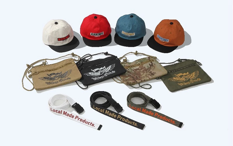 多頂帽子、斜背小包與腰帶排放,皆印有 OLDEN TIMES 與 Local Made Products 字樣