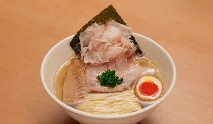 一碗有叉烧、葱花、溏心蛋、柴鱼片等配料的拉面