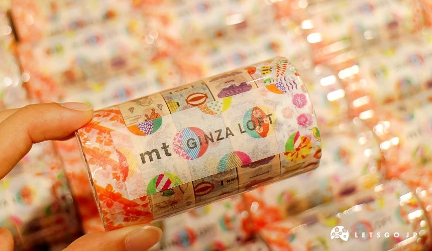 一隻手拿著一卷三個入的mt紙膠帶