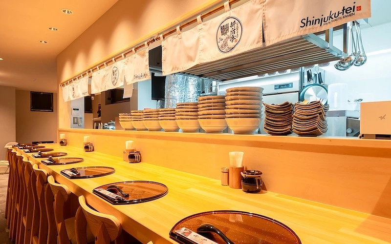 木頭的吧台桌上擺上著黑色餐墊上方有白色簾幕