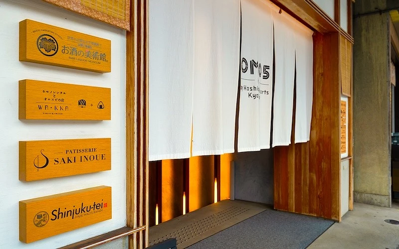 白色暖簾上面有英文字左邊柱子上有四塊木牌上面標示一些店面的名字