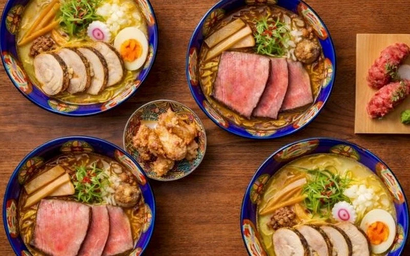 四碗上面盛放著不同料的拉麵中間有一份小菜右邊有一盤兩貫握壽司