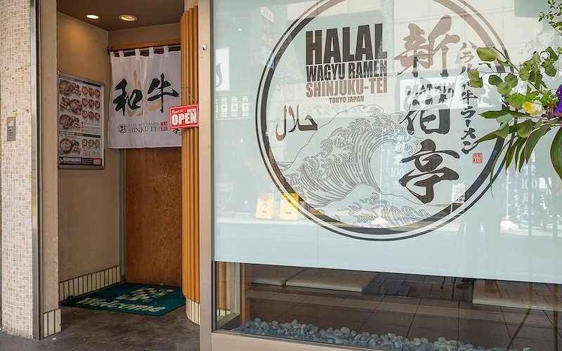 一間餐廳門口掛有白色布簾上面寫著新宿亭