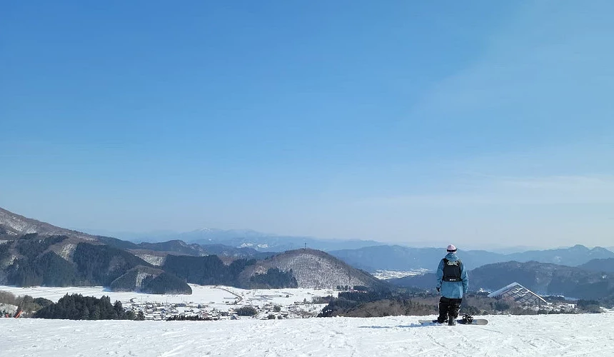 單板滑雪者站在雪道坡上眺望神鍋高原景色提供:日高神鍋観光協会