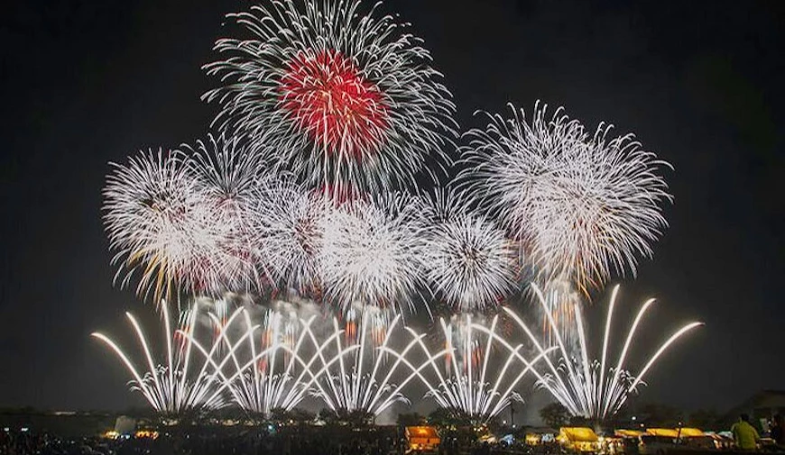 土浦花火大會2017年第86屆現場,夜空綻放多發大型紅白煙火,地面線狀煙火齊放,觀眾剪影