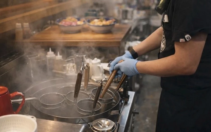 一位工作人員站在鍋爐前煮麵