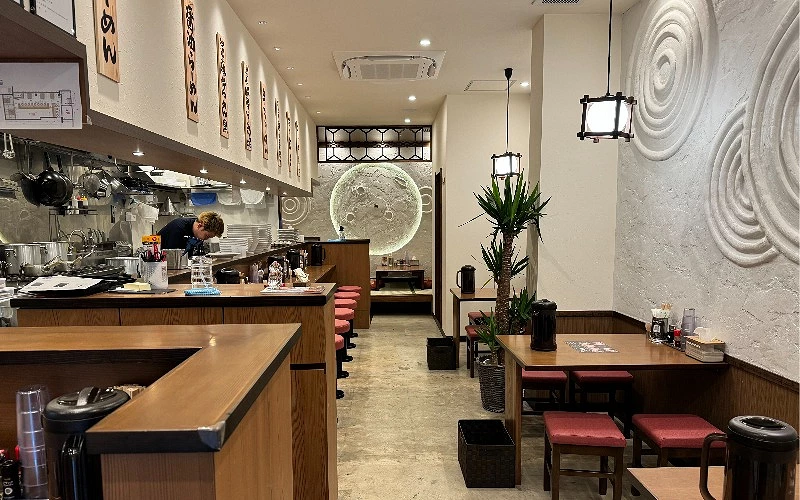拉麵店室內用餐區，吧台座位與廚房作業區