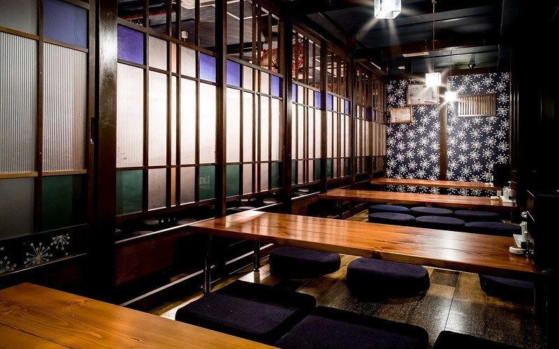 餐廳室內空間有木頭長型桌子及黑色坐墊