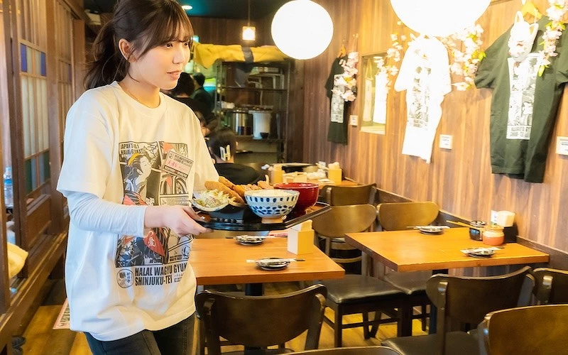 一位女子端著一份餐點走在餐廳室內空間