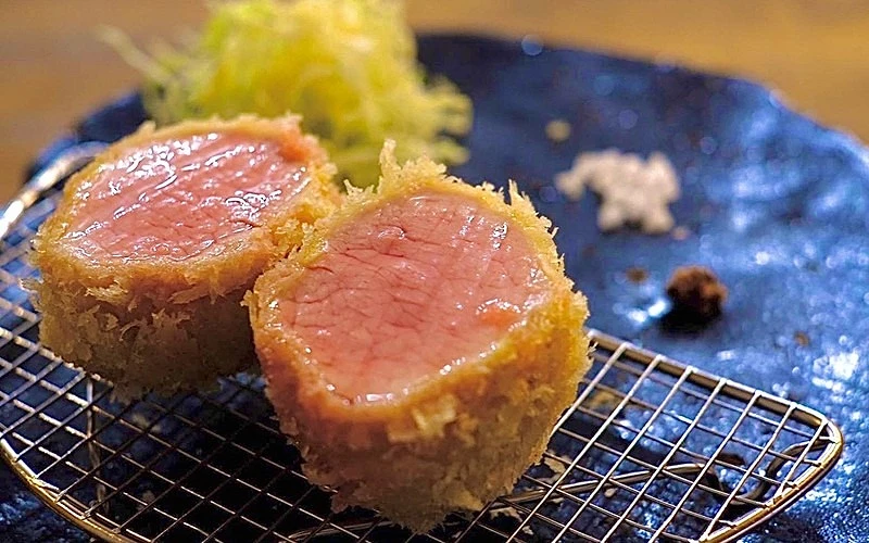 在藍色餐盤中剖面炸肉排擺放在金色瀝油網上