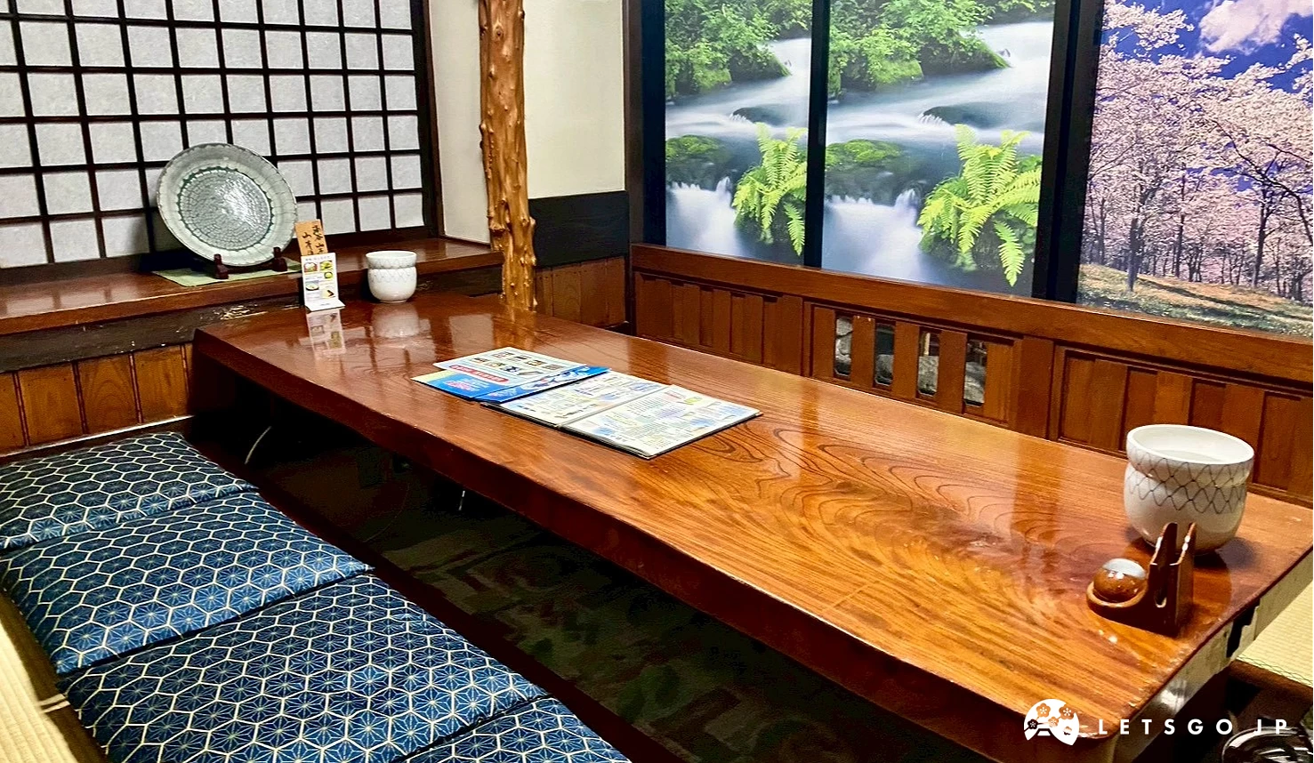 用餐桌位旁的牆面設有大型風景畫屏風，描繪森林、瀑布與櫻花盛開的自然美景，模擬日式庭園窗景。