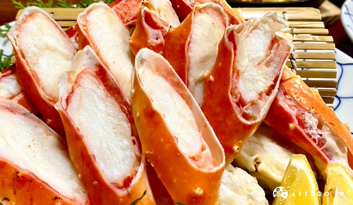 鱈場蟹肉的近距離特寫，展示其分明的肌肉纖維與濕潤的光澤感，背景隱約可見其他日式料理餐盤。