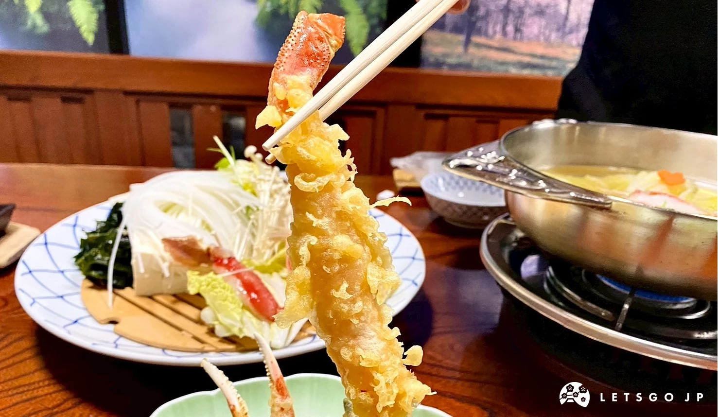 近距離特寫一張被筷子夾起的螃蟹天婦羅,金黃色的酥脆麵衣包裹著肥美的蟹腳