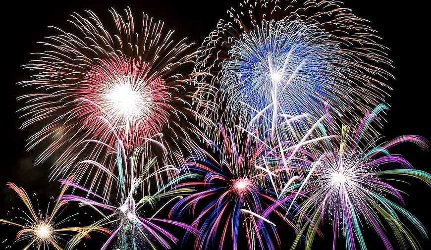 夜空中同時綻放的多組彩色煙火,包含粉紅、藍色、紫色等色彩的放射狀火花