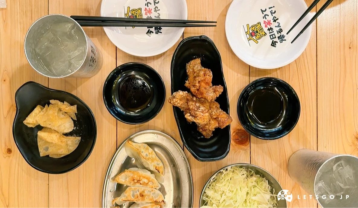 木紋桌上擺放炸雞、煎餃、啤酒等料理