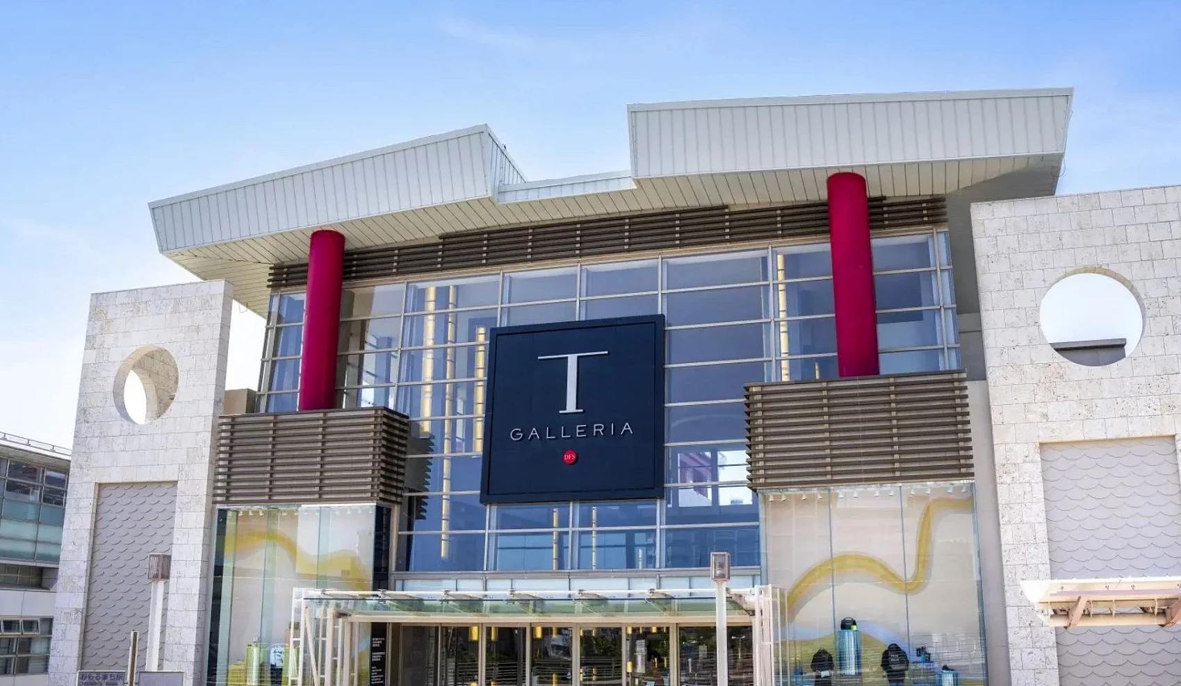 T Galleria 冲绳 by DFS 建筑外观,大型购物中心入口设计,红色立柱与玻璃帷幕立面构成现代风格商场