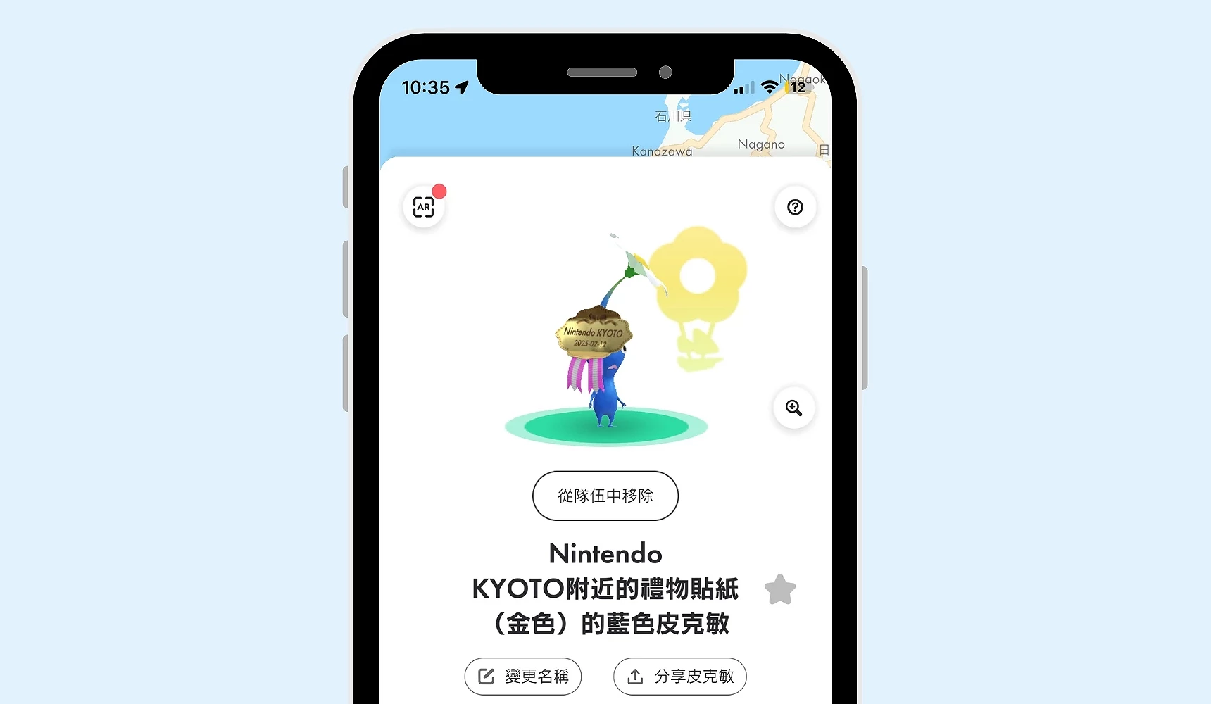 手机画面显示《Pikmin Bloom》蓝色皮克敏,头上配戴「Nintendo KYOTO」金色礼物贴纸装饰,为任天堂门市限定款皮克敏