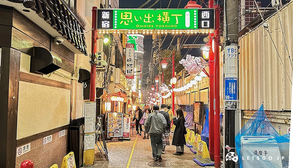 新宿西口「回忆横丁」入口绿色看板,街道两旁为狭窄巷弄。