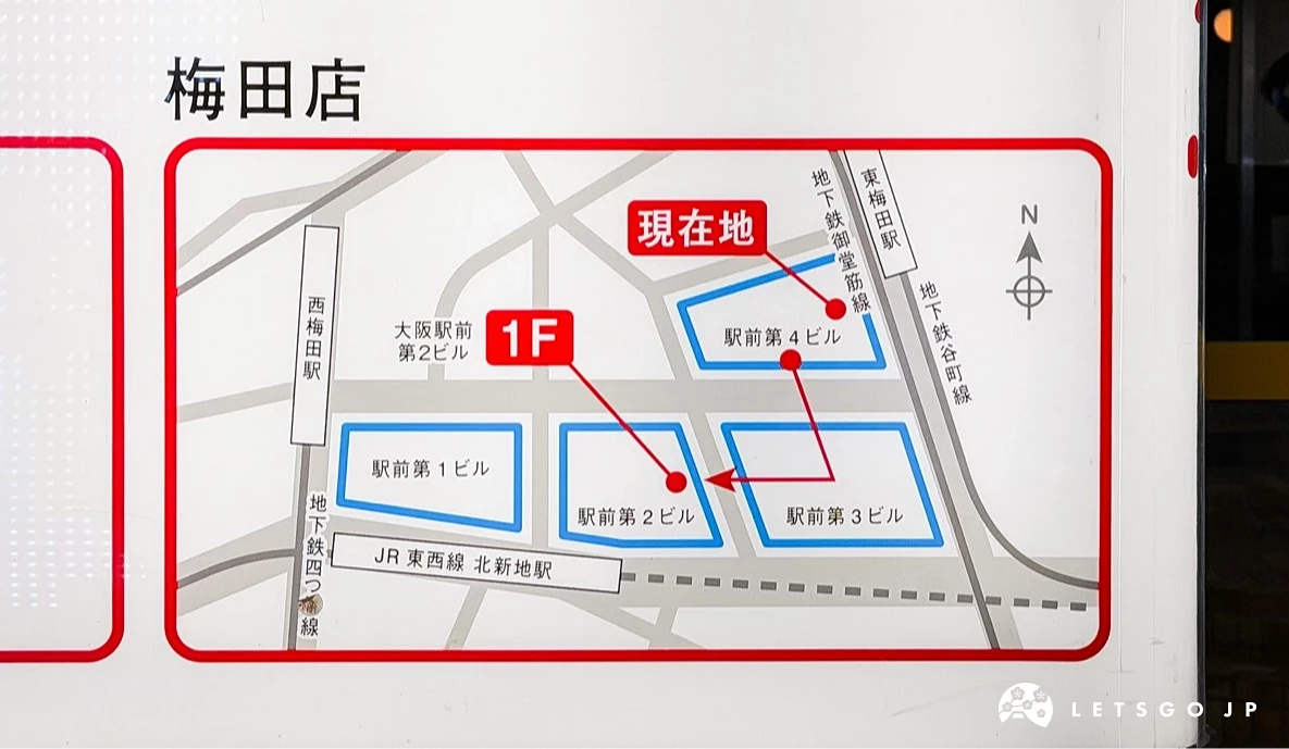 一块平面导览图。图上以红框标示「现在地」,并用蓝色实线箭头指引路径,路径经过「大阪駅前第 1 ビル」、「第 2 ビル」直至「JR 北新地站」。