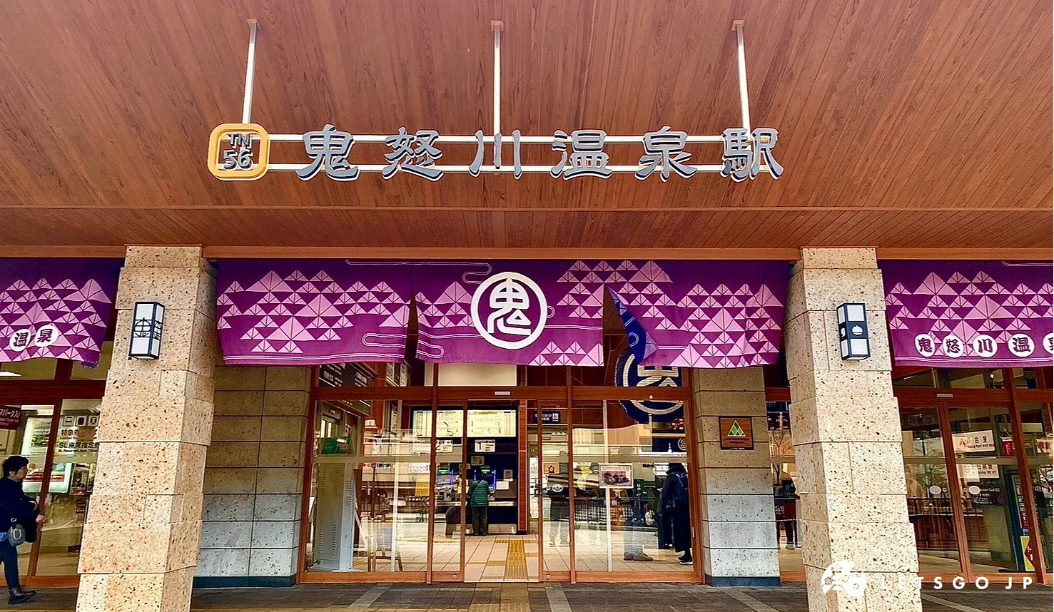 鬼怒川溫泉車站外觀,紫色暖簾上印有標誌,上方有木質飾板的站名看板。