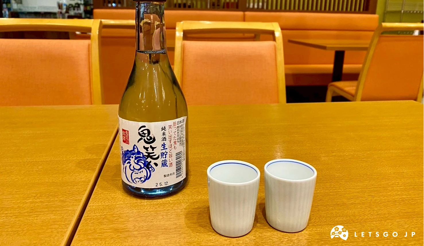 木質餐桌上放著一瓶栃木在地日本酒與兩只白色清酒杯。