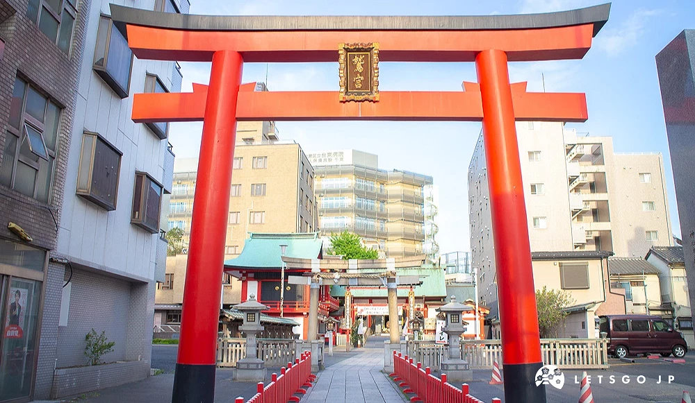 鷺宮神社紅色大型鳥居,後方可見石燈籠與現代建築。