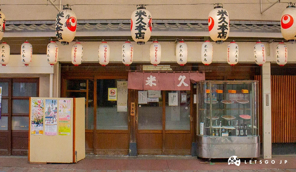 米久本店門口,上方懸掛多個日語標語燈籠並設有展示櫃。