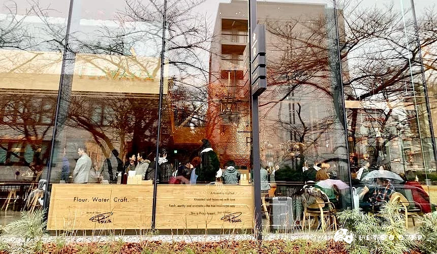 透过玻璃窗可见店内用餐人潮与户外街景倒影交错的画面