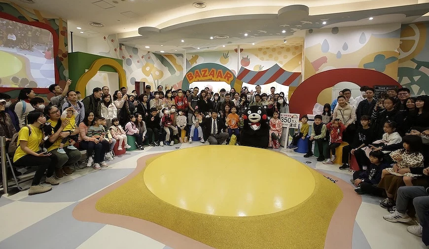 熊本熊與民眾在彩色主題場館內合影,手持寫有「350萬人達成」的慶祝看板,中間是360度舞台
