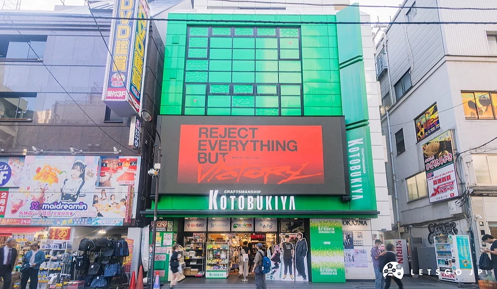 綠色建築門口上方有個大螢幕,動漫遊戲專賣店