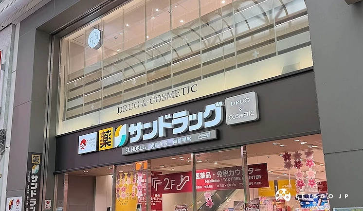 SUNDRUG 心齋橋中央店明亮的店面外觀,上方有大大的黑底白字招牌與紅黃藍三色標誌