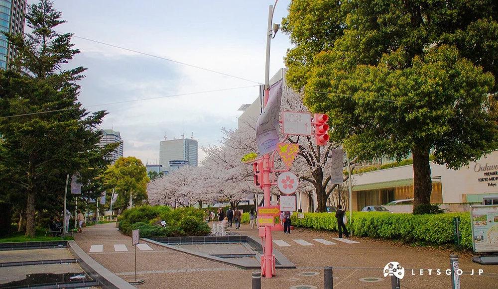六本木中城公园步道,粉红色灯柱旁有盛开的樱花与绿地。