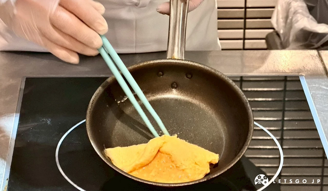 廚師正在平底鍋內製作色澤嫩黃的半熟歐姆蛋。