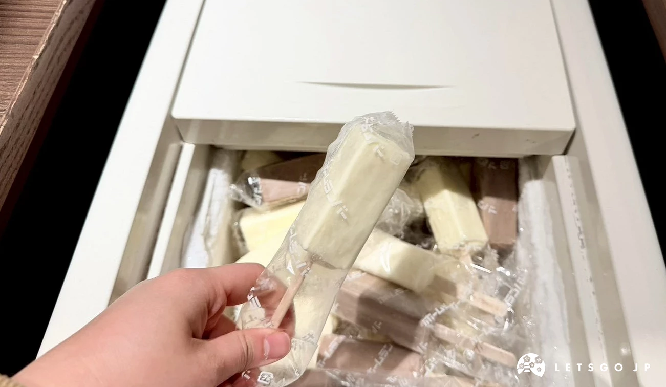一隻手正從冰櫃中取出一支包裝完整的免費雪糕冰棒。
