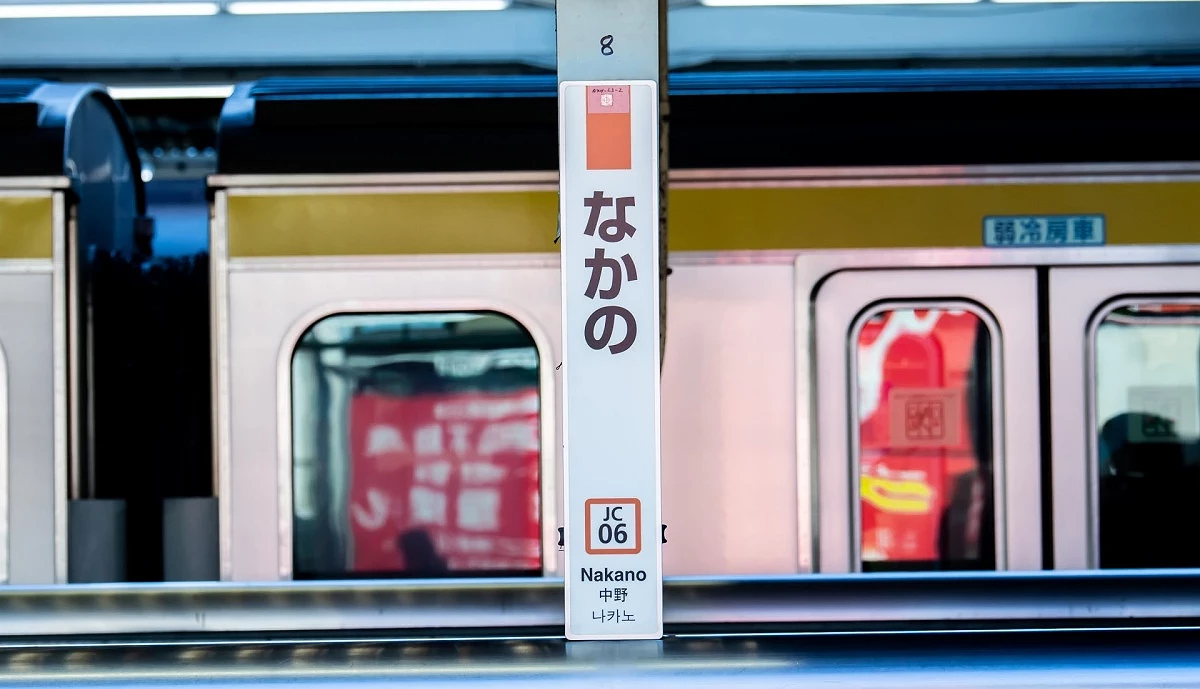 中野車站月台看板、背景有中央總武線行駛過