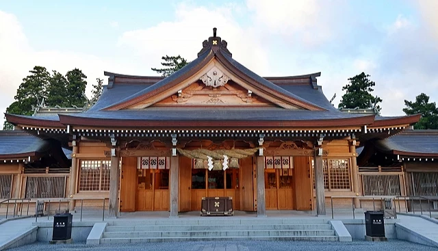 熊本縣阿蘇神社拜殿正面，木造建築屋頂下方懸掛注連繩，前方設有參拜步道