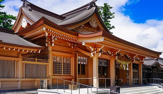 熊本縣阿蘇神社的木造拜殿側面，屋頂線條優美，前方設有參拜階梯與無障礙坡道