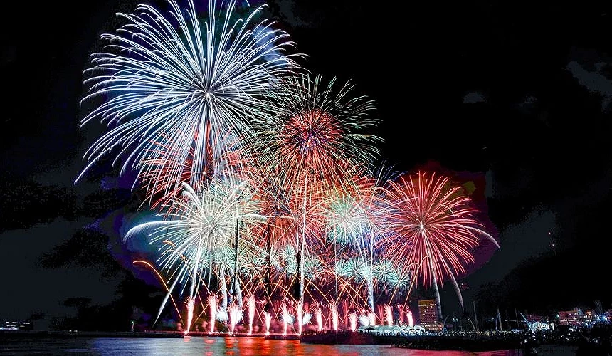 熱海海上花火大會於夜晚舉行，多彩大型煙火在海灣上空綻放，海面映照煙火光芒