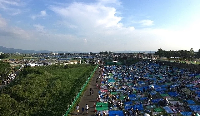 長岡花火會場白天景象,信濃川河川敷鋪滿藍色墊子與觀眾席,許多民眾提早佔位等待煙火開始