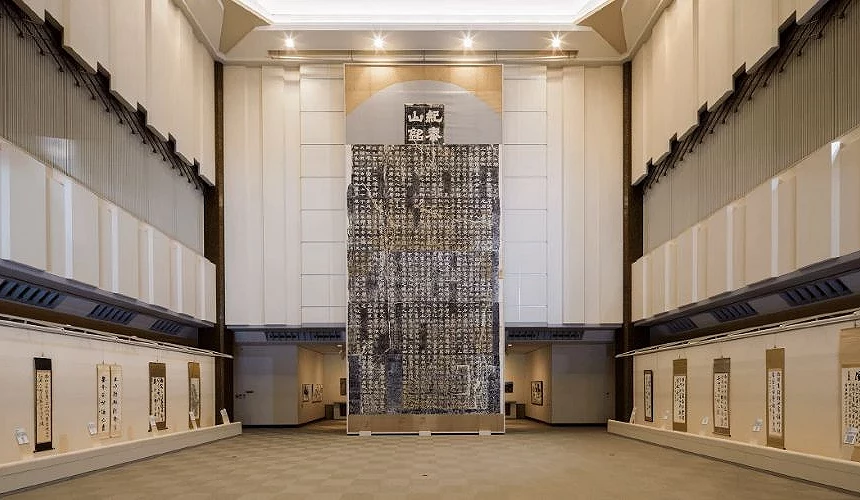 成田山書道美術館展覽空間,中央展示大型書法作品,館內牆面陳列多幅書道掛軸
