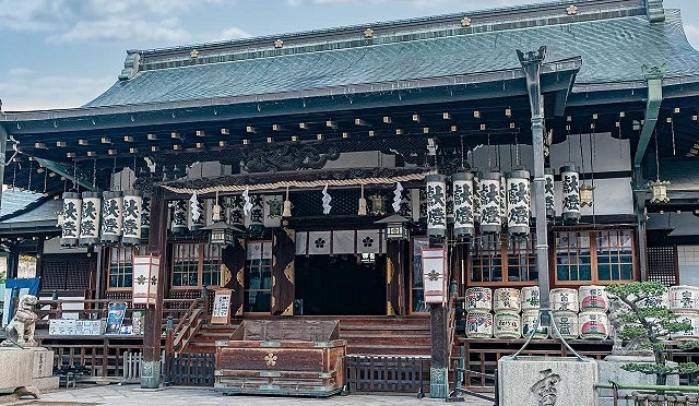 大阪天滿宮本殿建築正面，木造結構與綠色屋頂，前方設有賽錢箱與參拜空間